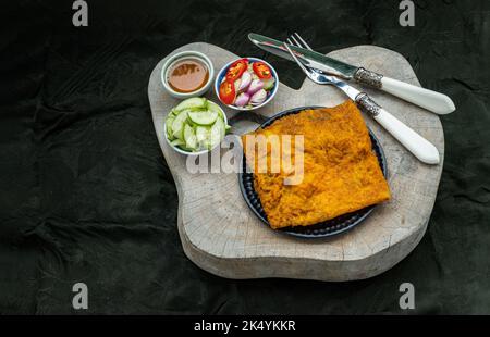 Knusprige vietnamesische herzhafte Crepe mit Garnelen (vietnamesische gefüllte knusprige Omelette oder gefüllte knusprige Eiercrepe), serviert mit Beilagen auf Holzhacken Stockfoto