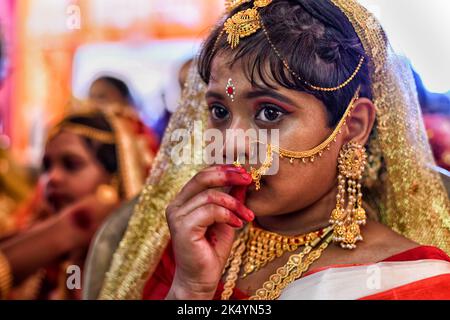 Kalkutta, Indien. 04. Oktober 2022. Ein kleines Mädchen sah während des Kumari Puja Rituals, wie es sich mit ihren Ornamenten fertig machte. Kumari Puja ist eine indische Hindu-Tradition, die hauptsächlich während der Durga Puja nach dem Hindu-Kalender gefeiert wird. Die philosophische Grundlage von Kumari Puja besteht darin, den Wert von Frauen zu ermitteln. Eifrige Anhänger glauben, dass sie alle Barrieren und Gefahren für die jungen Mädchen in der kommenden Zukunft überwinden werden, und sie werden auch befugt sein, jeden Stress und jede Behinderung in ihrem kommenden Leben zu bewältigen. Kredit: SOPA Images Limited/Alamy Live Nachrichten Stockfoto