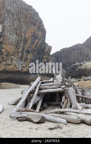 Eine Treibholzstruktur und eine Felsformation am Seal Rock State Park Strand in der Nähe von Newport, Oregon. Stockfoto
