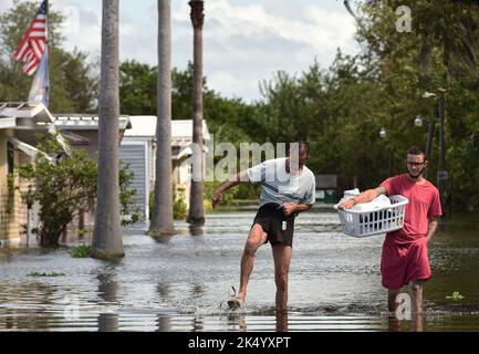 St. Cloud, Usa. 04. Oktober 2022. Ron Harris (L) und Anthony Bednarz (R) waten durch eine überflutete Straße im Jade Isle Mobile Home Park in St. Cloud. Die Bewohner der Gemeinde wurden aufgrund des Anstiegs des Wasserspiegels nach dem Orkane Ian freiwillig evakuiert. Kredit: SOPA Images Limited/Alamy Live Nachrichten Stockfoto