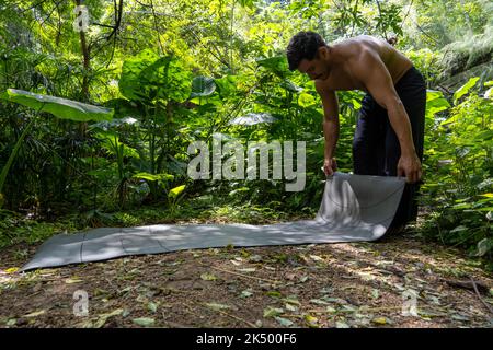 Junger latein, der seine Yogamatte arrangiert, in einem Wald auf einem Ebenen, direkten Kontakt mit der Natur, mexiko Stockfoto