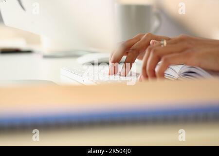 Nahaufnahme von weiblichen Händen, die auf Tastatur und Tagebuch tippen Stockfoto