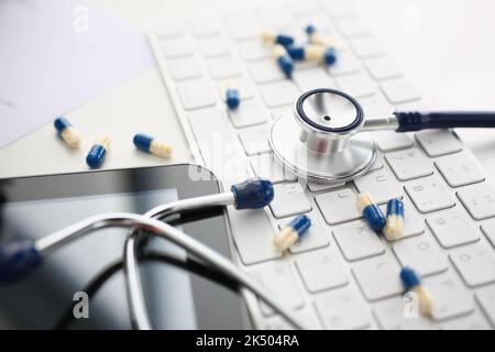 Tabletts und Stethoskop auf der Computertastatur in Nahaufnahme Stockfoto