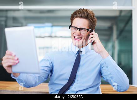 Ich bin davon sehr beeindruckt. Ein begeisterter Geschäftsmann, der einen Anruf entgegennimmt und auf seinen Tablet-Bildschirm schaut. Stockfoto