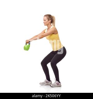 Ein komplettes Workout. Eine wunderschöne blonde Frau, die eine zweihändige Kugelhantel-Schaukel spielt. Stockfoto