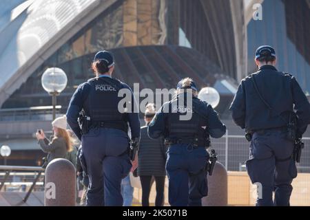 Drei Polizisten aus New South Wales, die morgens mit Seitenarmen auf einer Fußpatrouille unterwegs sind, laufen um den Vorplatz des Opernhauses von Sydney in Australien Stockfoto