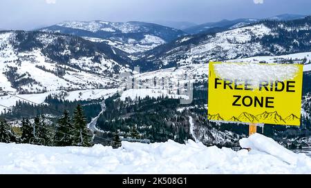 Gelbes Symbol mit Warnung vor Freifahrzone im Skigebiet im Winter auf verschneiten Bergen. Free Ride Zone auf dem Berg in der Ukraine Karpaten Berg Gefahrenschild für Skifahrer und Snowboarder Stockfoto