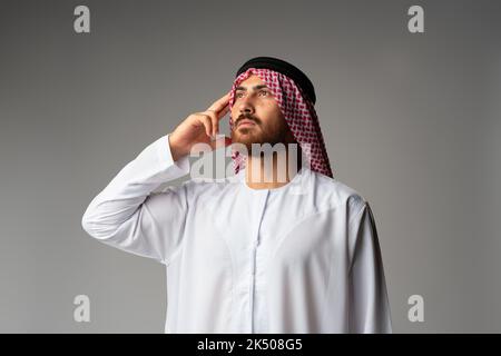 Junger arabischer Mann in traditioneller Kleidung, der an etwas denkt Stockfoto