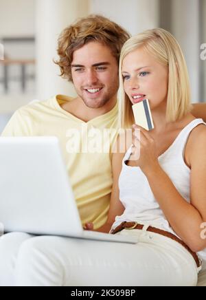 Online zu kaufen ist schnell und einfach. Ein glückliches junges Paar, das online mit seiner Kreditkarte kauft. Stockfoto