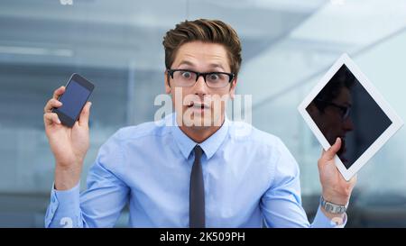 Ich wurde von jeder Ecke kontaktiert. Ein überraschender junger Geschäftsmann mit einem Tablet und einem Smartphone. Stockfoto