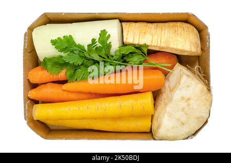Frische Wintersuppe, ungeschnitten und vorverpackt, in einem Papptablett, von oben, isoliert über weiß. Karotten, Sellerie, Pastinaken, Lauch und Petersilie. Stockfoto