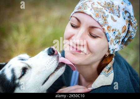 Ein junges Mädchen, das mit einem Hund im Park spazierenging, den Hund Husky umarmte und küsste. Stockfoto