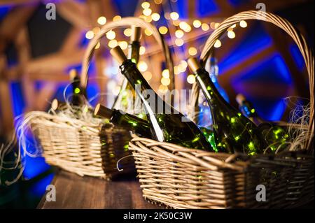 Sektflasche Set mit Weihnachtskorb, goldene Girlanden auf dunkelbraunem Holzhintergrund, Konzept zur Feier des neuen Jahres Stockfoto