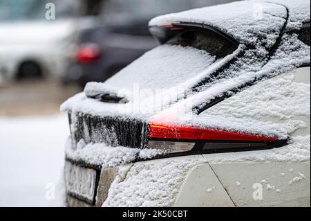 Autos, die auf verschneiten Straßen geparkt wurden, Seitenansicht hinten, selektiver Fokus auf die Heckleuchten Stockfoto