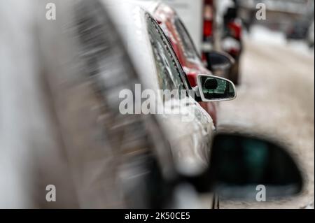 Autos auf verschneiten Straßen geparkt, Rückansicht, selektiver Fokus auf Rückspiegel Stockfoto