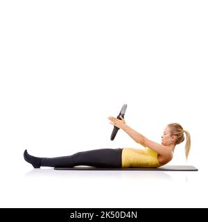 Fitness und Gesundheit sind ihr wichtig. Eine hübsche junge Blondine, die die Roll-up-Übung mit ihrem Pilates-Ring durchführt. Stockfoto