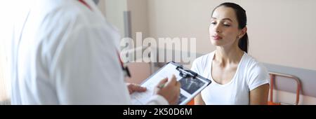 Arzt in Maske kommuniziert mit dem Patienten in der Klinik Stockfoto
