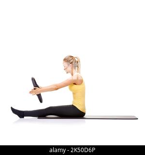 Ihre Kernmuskeln fesseln. Eine hübsche junge Blondine, die die Roll-up-Übung mit ihrem Pilates-Ring durchführt. Stockfoto