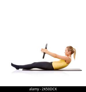 Shell haben einen straffen Magen für den Sommer. Eine hübsche junge Blondine, die die Roll-up-Übung mit ihrem Pilates-Ring durchführt. Stockfoto
