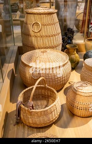 Große runde Korbkörbe aus Rattan mit Deckeln für die Inneneinrichtung viel auf Lager. Verschiedene Typen. Vorderansicht, Lifestyle, vertikales Foto. Stockfoto