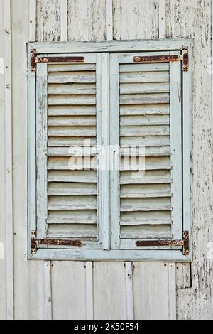 Holzfenster und Fensterläden im Haus bei Sonnenuntergang blau gestrichen Stockfoto