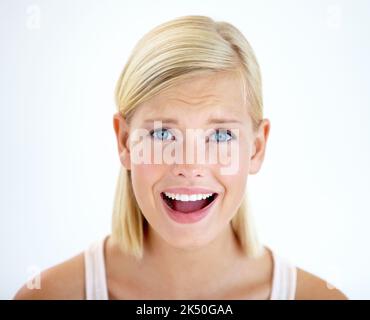 Unglaube. Porträt einer hübschen jungen Frau, die ungläubig lächelt. Stockfoto