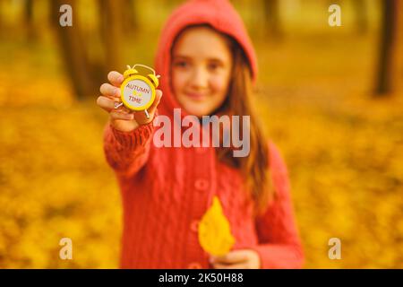 Nettes Mädchen hält einen Wecker im Herbst Park. Stockfoto