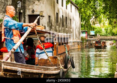 Ein Bootsmann rudert ein Touristenboot auf dem Pingjiang Fluss entlang der Pingjiang Lu, einer Straße voller alter Gebäude in Suzhou, Provinz Jiangsu, China. Stockfoto