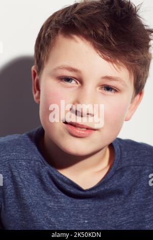 Positiv über seine Zukunft. Beschnittenes Porträt eines jungen jungen Jungen, der vor einem weißen Hintergrund lächelt. Stockfoto