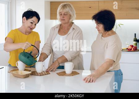 Reife Frau auf einer Tee-Party. Drei Freunde trinken gemeinsam Tee in einem Haus. Stockfoto
