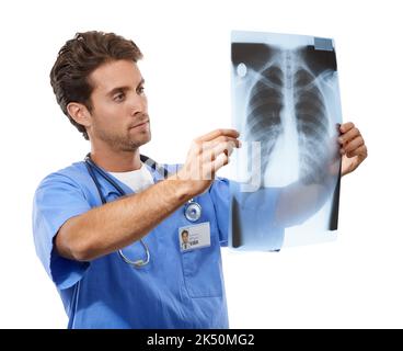Konzentration auf die Suche nach einer Behandlung. Studioaufnahme eines hübschen jungen Arztes, der einen Röntgenstrahl untersucht, den er gerade hält. Stockfoto