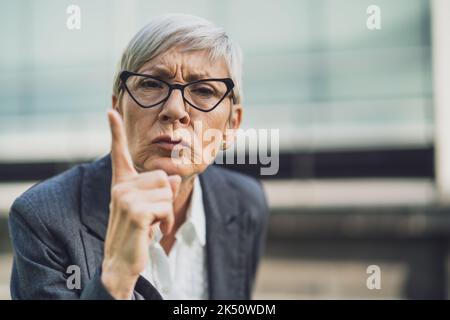 Nahaufnahme des Porträts einer älteren Geschäftsfrau, die wütend ist und droht. Stockfoto
