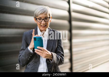 Außenportrait einer erfolgreichen Geschäftsfrau, die auf dem Smartphone chattet. Stockfoto