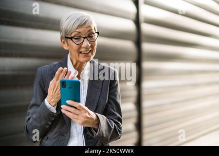 Außenportrait einer erfolgreichen Geschäftsfrau, die auf dem Smartphone chattet. Stockfoto