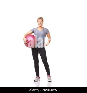 Selbstbewusst im Hinblick auf Bewegung. Eine schöne junge Frau in einer Gymnastik, die einen Medizinball hält. Stockfoto