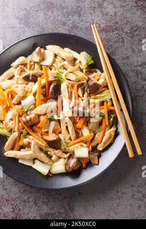 Suey Chicken mit Gemüse in der Nahaufnahme auf einem Teller auf dem Tisch frites Huhn hacken. Vertikale Draufsicht von oben Stockfoto