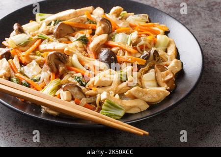 Chop Suey ist ein schnelles chinesisch-amerikanisches Rührbraten mit Huhn und gemischtem Gemüse in einer dicken braunen Sauce in Nahaufnahme auf einem Teller auf dem Tisch. Horizontal Stockfoto