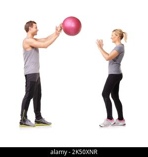 Fit zu werden macht Spaß. Ein Mann und eine Frau trainieren, indem sie sich einen Medizinball zuwerfen. Stockfoto