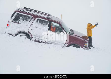 Frau erlitt einen Unfall im Schnee mit ihrem Auto inmitten eines eisigen Sturms. Stockfoto