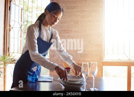 Die Kellnerin im Restaurant putzte nach dem Essen das Geschirr vom Tisch. Kundenservice, Abendessen und Arbeit in der Lebensmittelindustrie als Kellner, der schmutzig abräumte Stockfoto