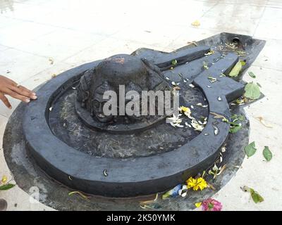 Eine Shiva Linga, die mit einem schwarzen Stein auf einer Ebenen Oberfläche mit einer Umgebung aus Fliesen hergestellt wurde Stockfoto