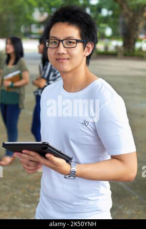 Mit moderner Technologie für das Finale zu studieren. Porträt eines hübschen jungen Studenten, der draußen an seinem digitalen Tablet arbeitet. Stockfoto