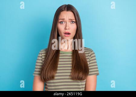 Foto von süßen wunderschönen unglücklichen Mädchen mit geraden Frisur gekleidet gestreiften T-Shirt beleidigt offenen Mund isoliert auf blauem Hintergrund Stockfoto