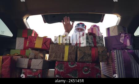 weihnachtsmann liefert Geschenke. Geschenke vom weihnachtsmann. Lieferservice. Deliveryman lädt Boxen. Geschenk-Boxen im Auto. Schön verpackte Pakete. Blick aus dem Inneren des Autos. Spende, Wohltätigkeit oder Lieferkonzept. Hochwertige Fotos Stockfoto
