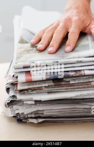 Reduzieren, wiederverwenden, recyceln. Eine Hand auf einem Stapel von Zeitungen. Stockfoto
