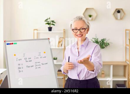 Portrait einer freundlichen älteren Lehrerin, die während des Fernunterrichts die Regeln der englischen Grammatik erklärt Stockfoto