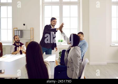 Kollegen, die sich bei einem geschäftlichen Meeting im Büro mit fünf Mitarbeitern gegenseitig begrüßen oder Respekt ausdrücken Stockfoto