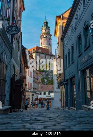 Der Blick auf den Turm der Burg Cesky Krumlov von der Straße der Altstadt. Touristen im Vordergrund. Český Krumlov, Südböhmen, Tschechische Republik Stockfoto