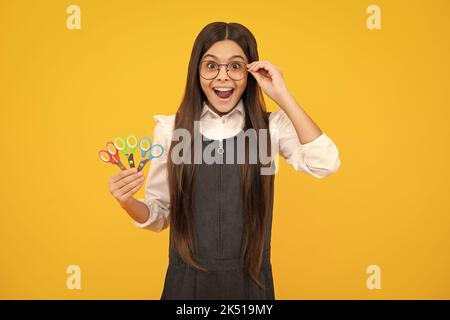 Kinder Kreativität, Kunst und Handwerk. Teenagermädchen mit Schere, isoliert auf gelbem Hintergrund. Stockfoto