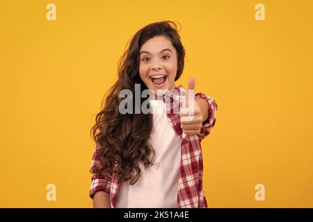 Ein erstaunlicher Teenager. Glücklich lustige Teenager Kind Mädchen zeigen Anblick Daumen nach oben und Viel Glück. Aufgeregt teen Mädchen. Stockfoto